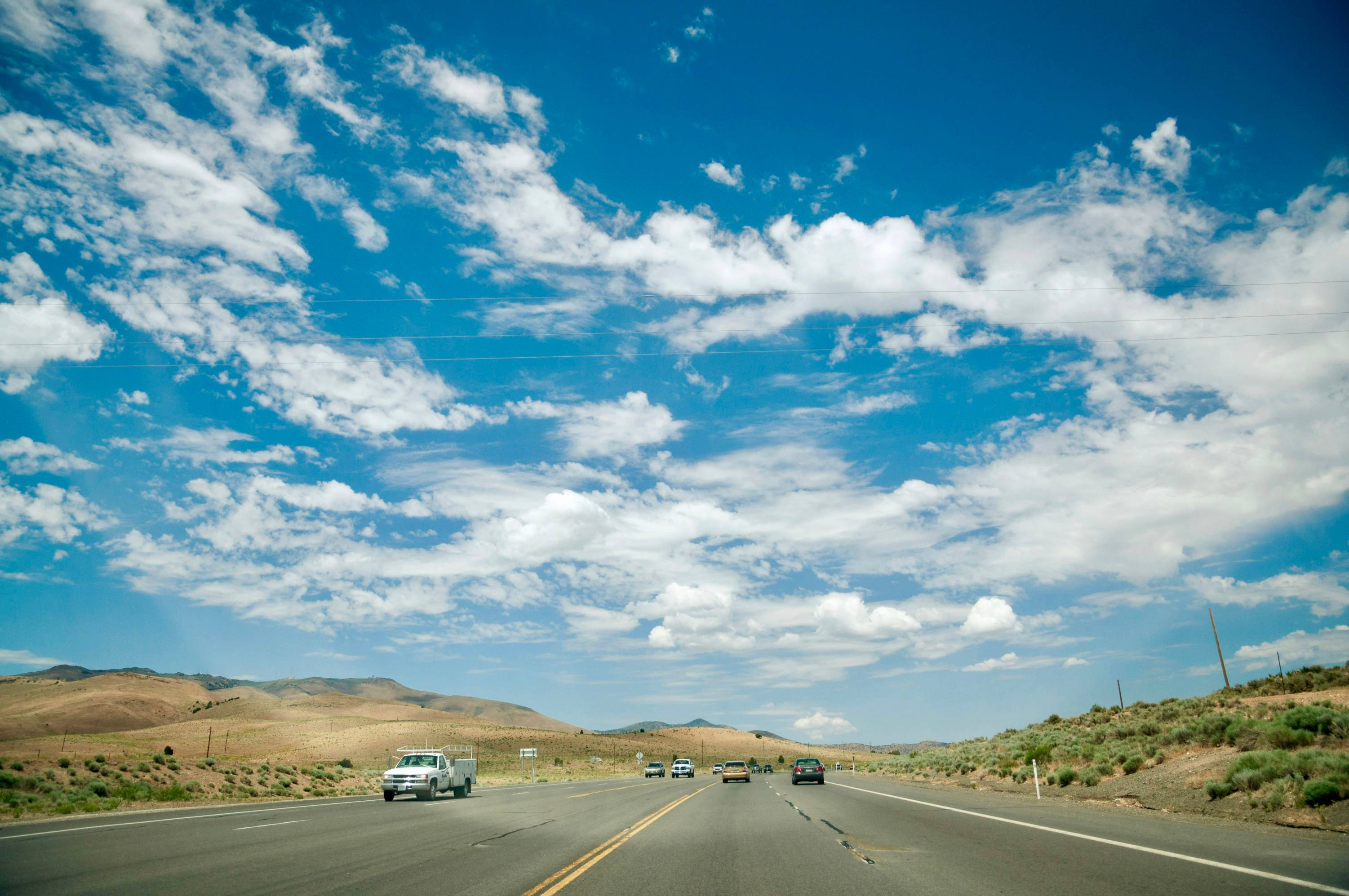 vehicles on road under cloudy sky during daytime