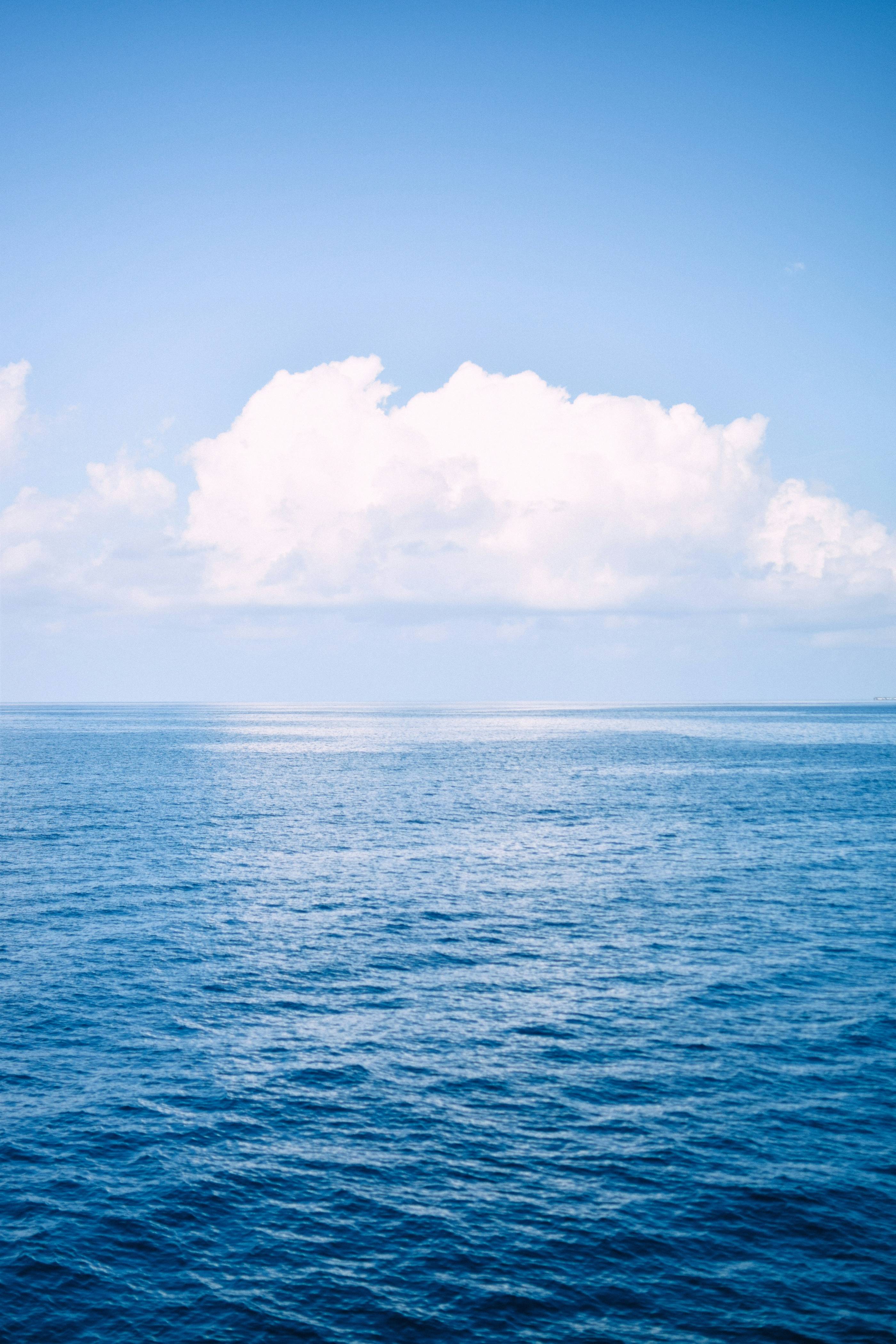 a large body of water under a cloudy blue sky